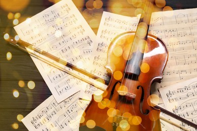 Image of Christmas and New Year music. Violin and music sheets on wooden background, bokeh effect