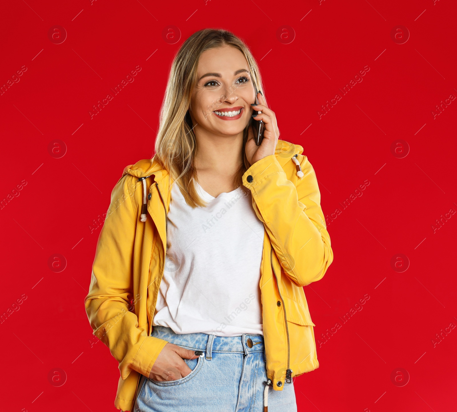 Photo of Beautiful woman talking on smartphone against red background