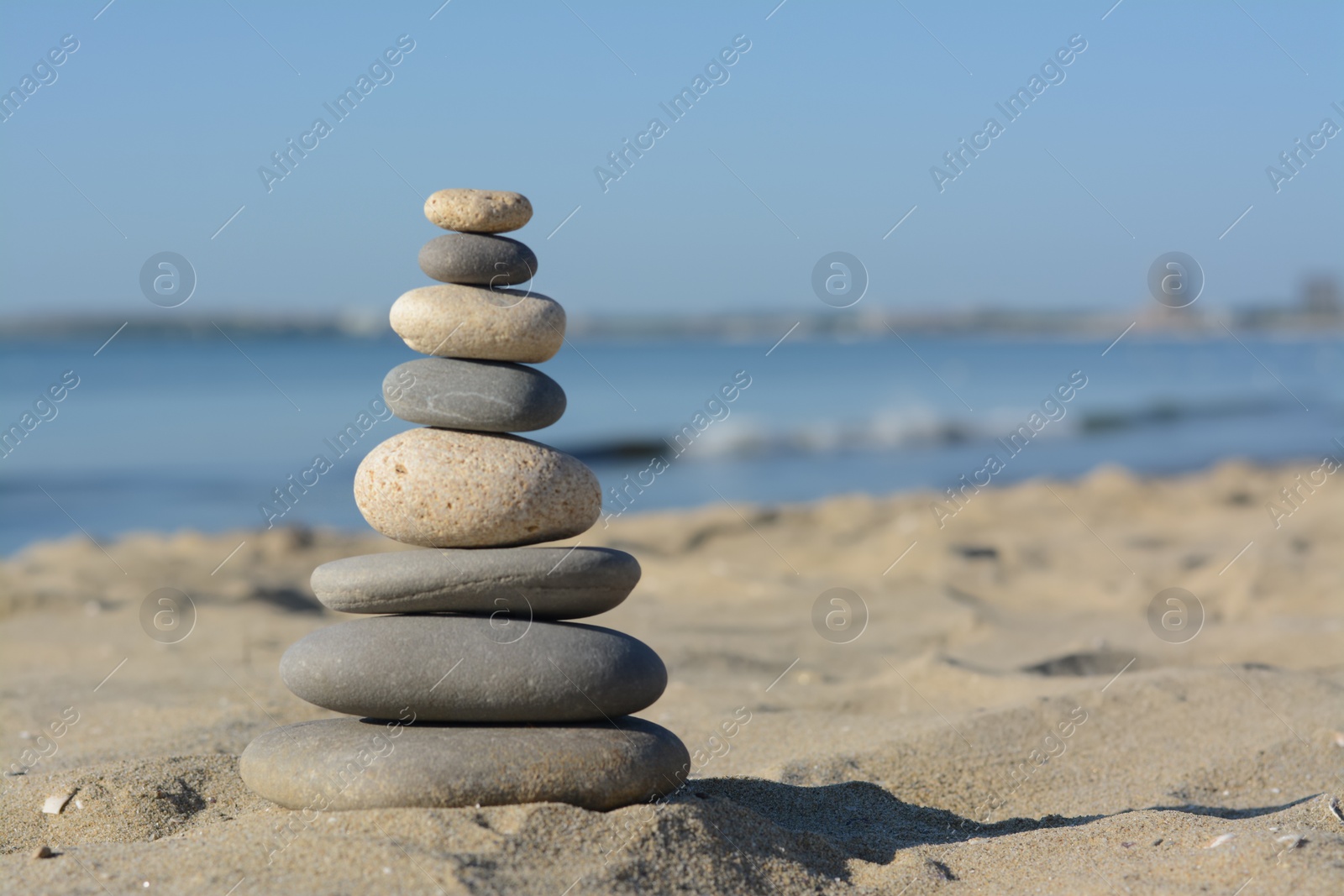 Photo of Stack of stones on sandy beach, space for text