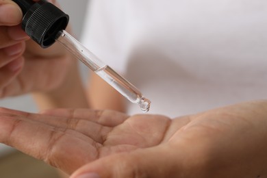 Photo of Woman applying cosmetic serum onto her hand, closeup