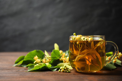 Photo of Cup of tea and linden blossom on wooden table. Space for text