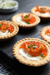 Photo of Delicious canapes with shrimps, red caviar and cream cheese on dark table, closeup