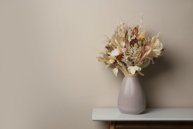 Photo of Beautiful dried flower bouquet in ceramic vase on white table near light grey wall. Space for text