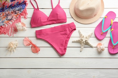 Photo of Beautiful pink bikini and beach accessories on white wooden background, flat lay