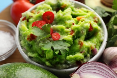 Photo of Delicious guacamole and ingredients on table, closeup