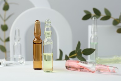 Photo of Stylish presentation of different skincare ampoules on white background, closeup