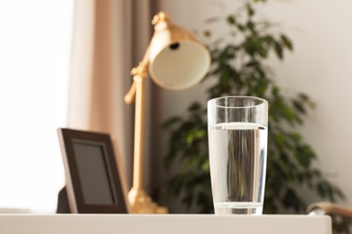 Glass of fresh water on table indoors. Space for text