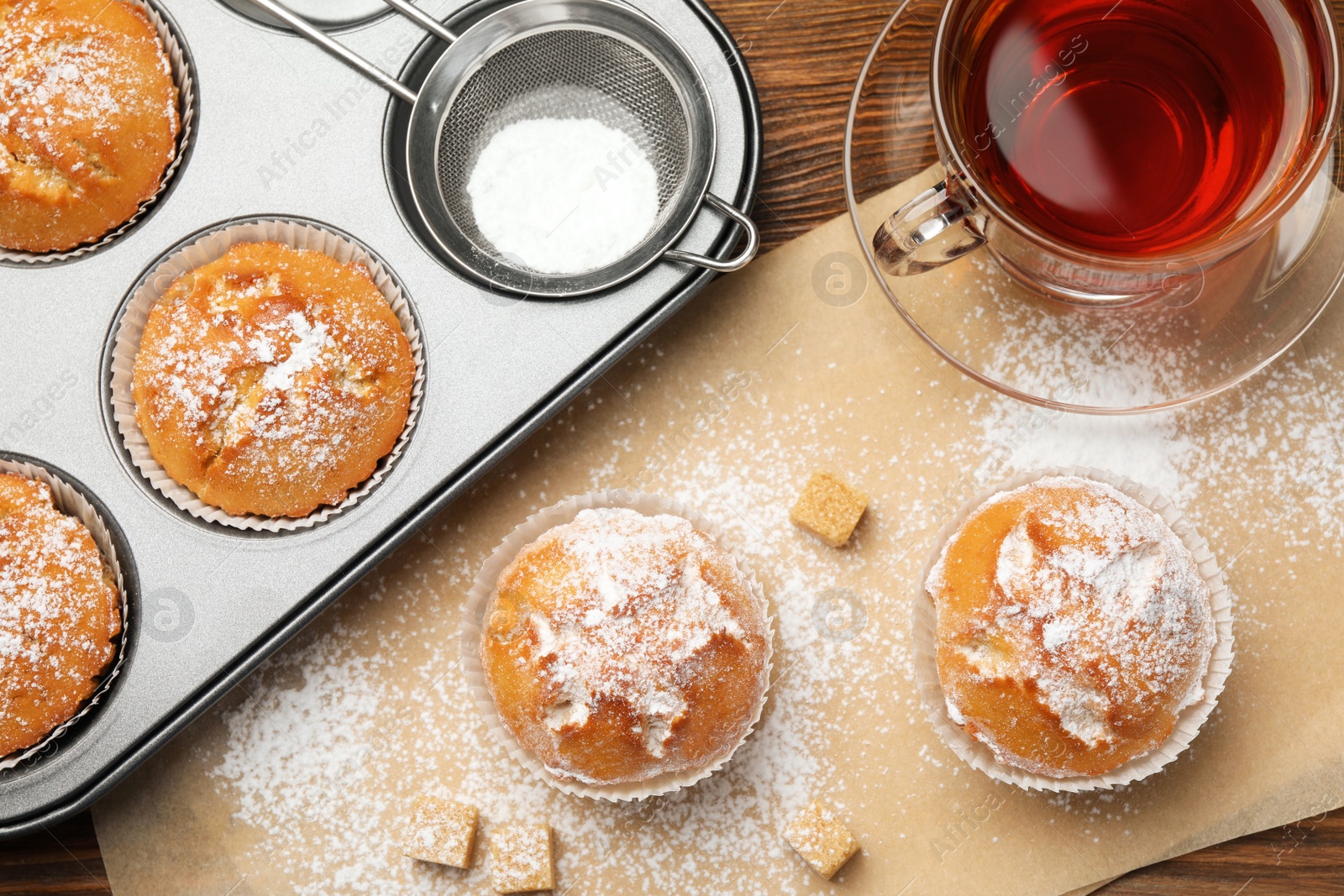 Photo of Flat lay composition with homemade muffins and tea on wooden table