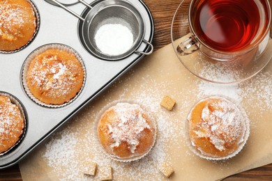 Photo of Flat lay composition with homemade muffins and tea on wooden table