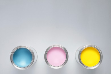 Photo of Cans with colorful paints on light background, flat lay. Space for text