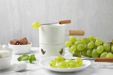 Fondue pot and grapes on marble table