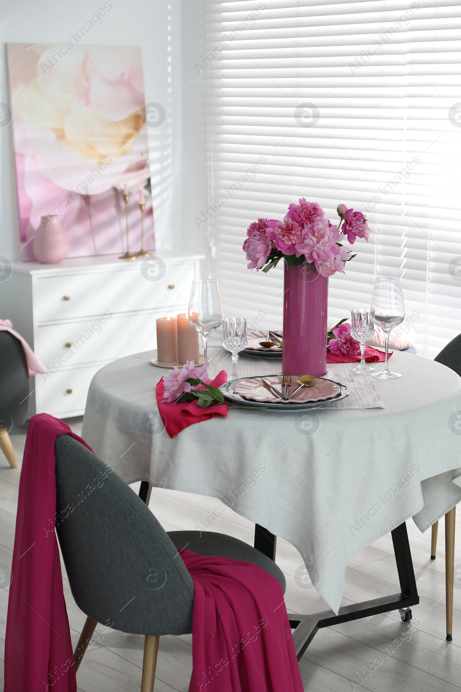 Photo of Pink peonies on table with beautiful setting and chair in dining room