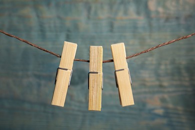 Photo of Clothespins on rope against light blue wooden background, closeup