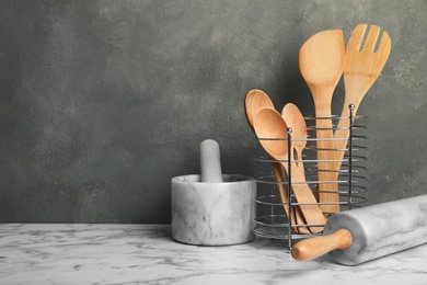 Different kitchen utensils and mortar on table. Space for text