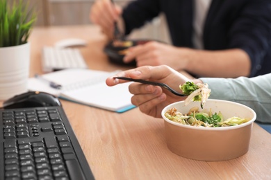 Photo of Office employees having lunch at workplace, closeup. Food delivery