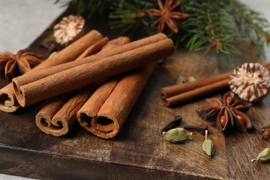 Photo of Different aromatic spices and fir branches on wooden board, closeup
