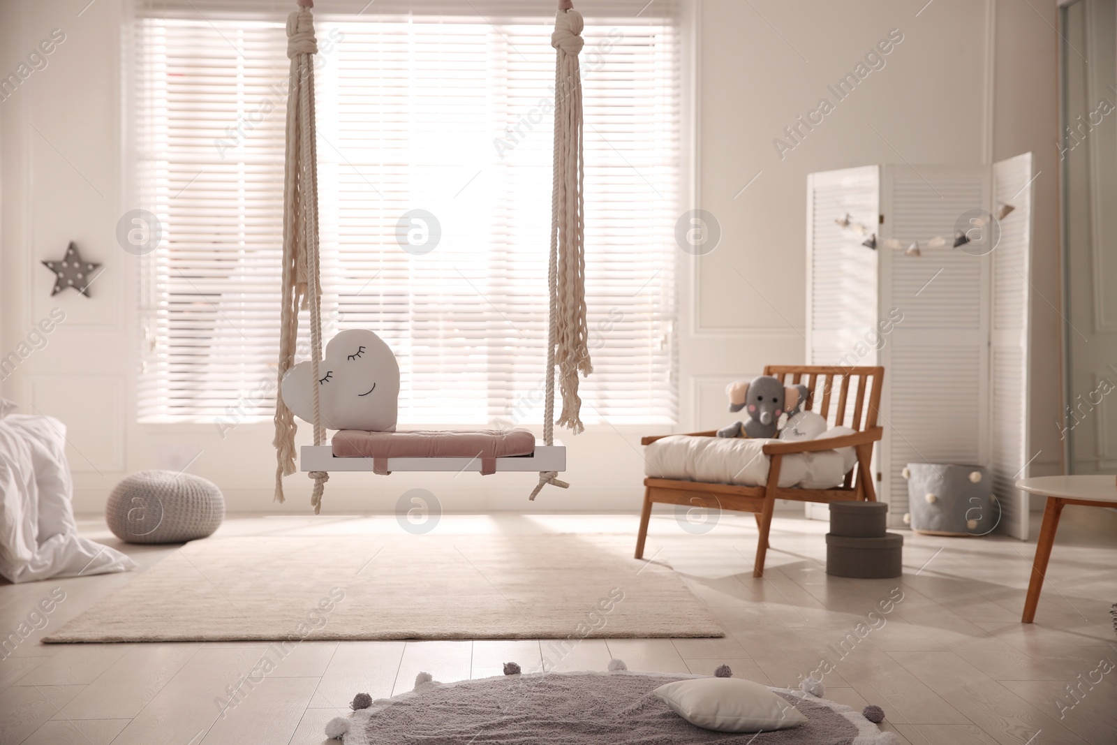 Photo of Beautiful swing with toy heart in room. Stylish interior design