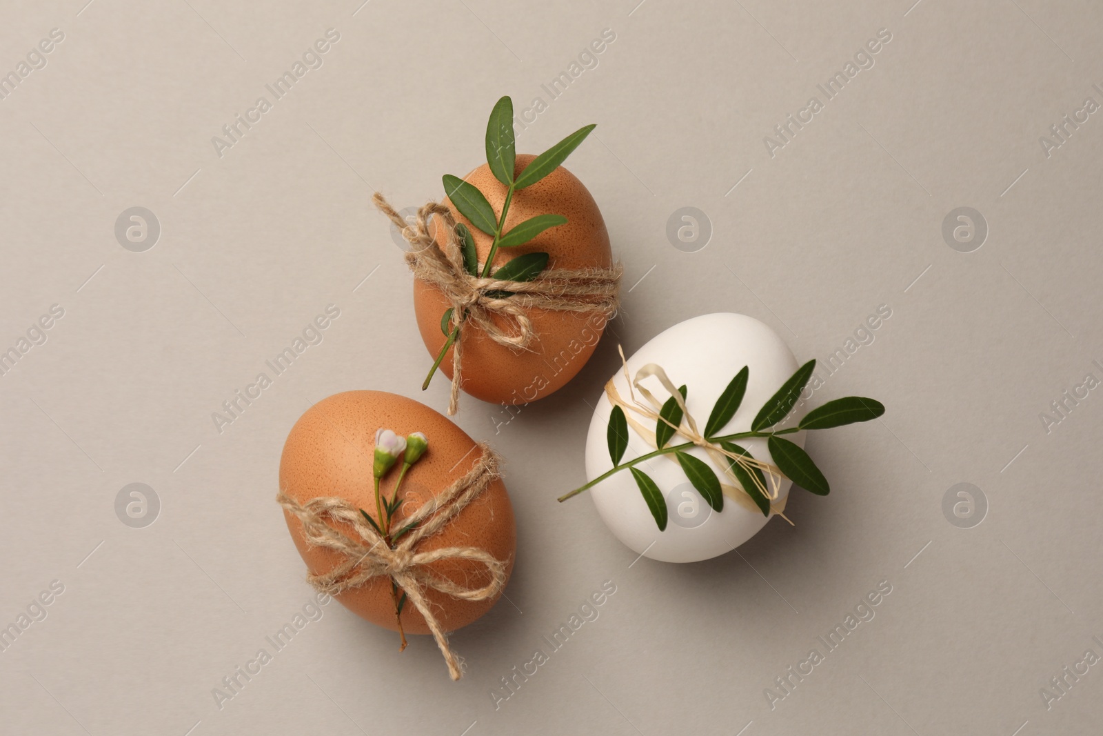 Photo of Chicken eggs and natural decor on light grey background, flat lay. Happy Easter