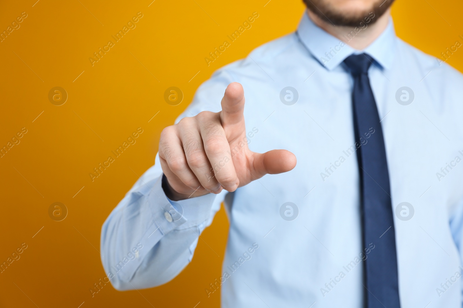 Photo of Businessman touching something against orange background, focus on hand