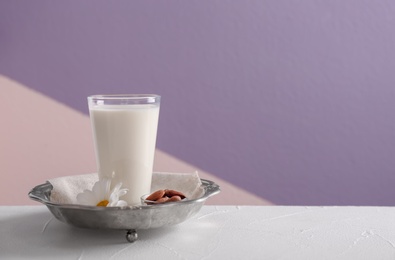 Photo of Glass of milk on vintage plate against color background