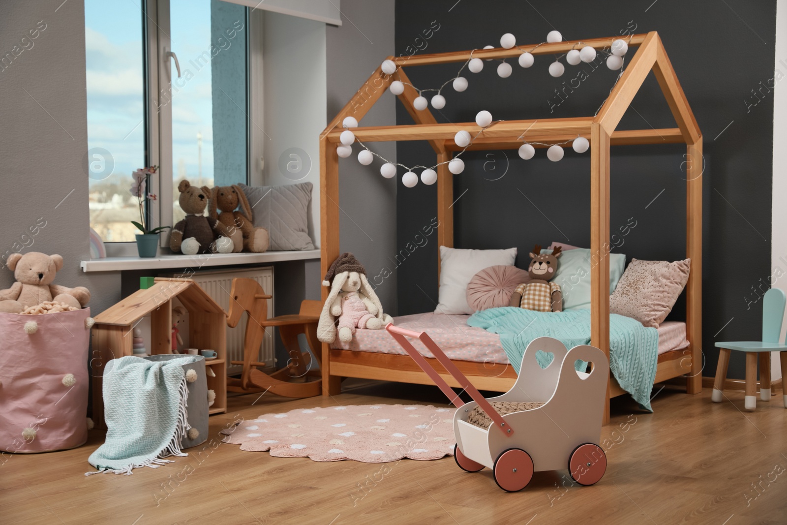 Photo of Stylish child room interior with wooden bed in shape of house and toys