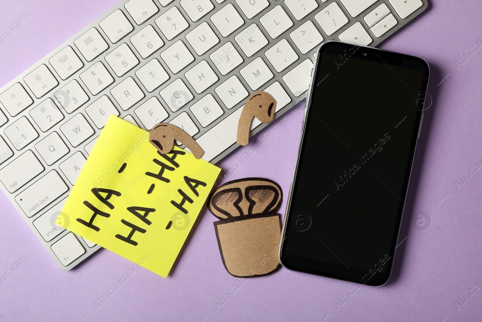 Photo of Keyboard, smartphone and carton earphones on violet background, flat lay. April fool's day