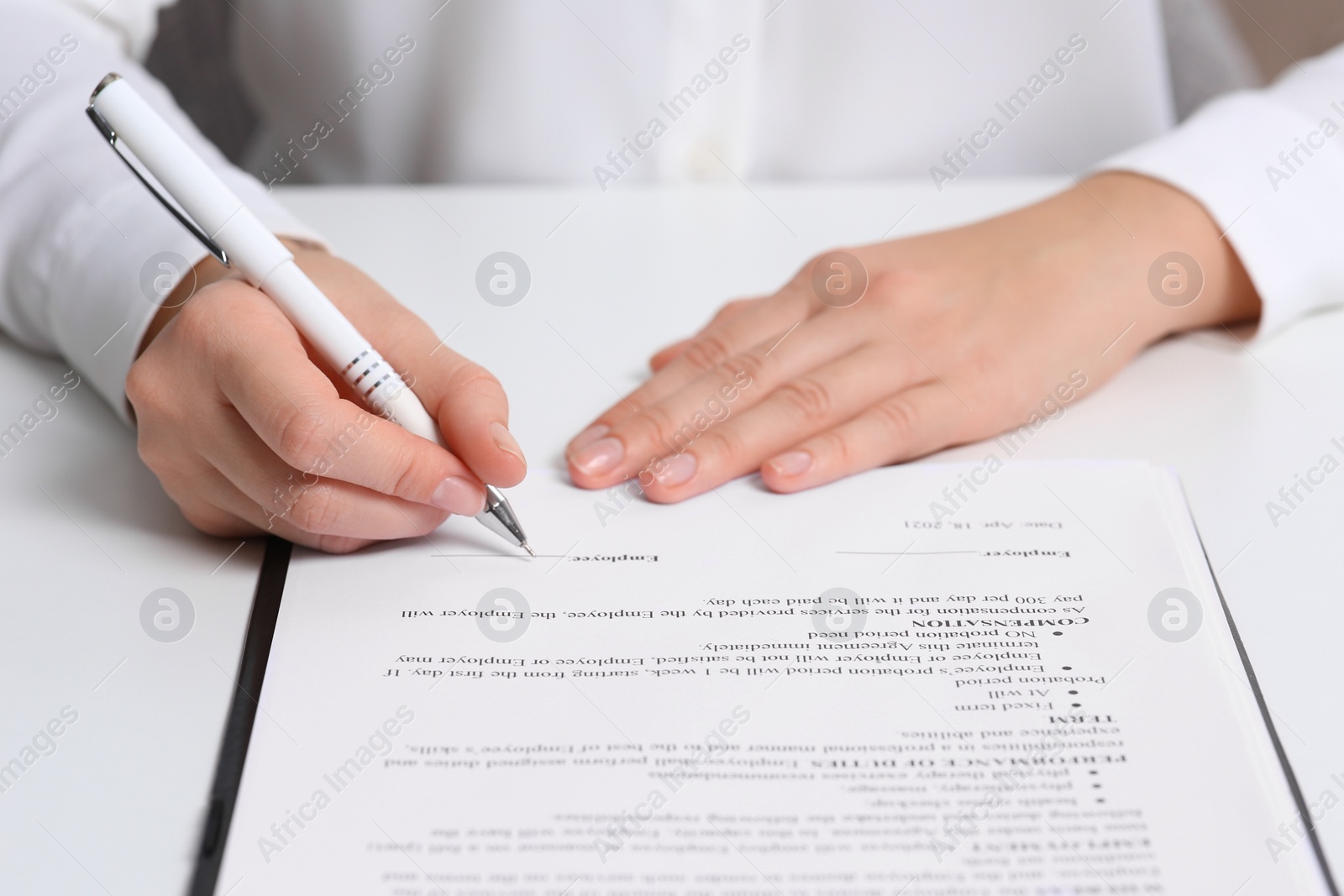 Photo of Businesswoman signing contract at white table, closeup of hands