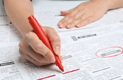 Photo of Woman marking advertisement in newspaper, closeup. Job search concept