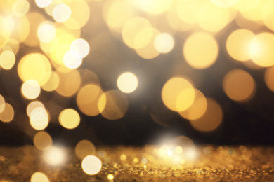 Blurred view of gold glitter on dark background, bokeh effect