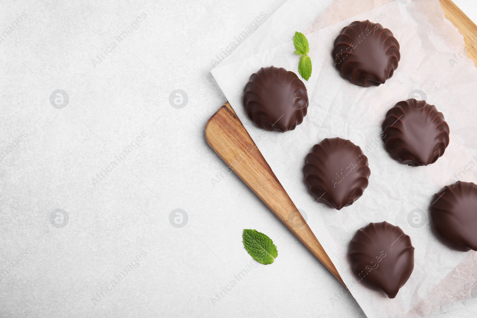 Photo of Delicious chocolate covered zephyrs and mint on white table, flat lay. Space for text