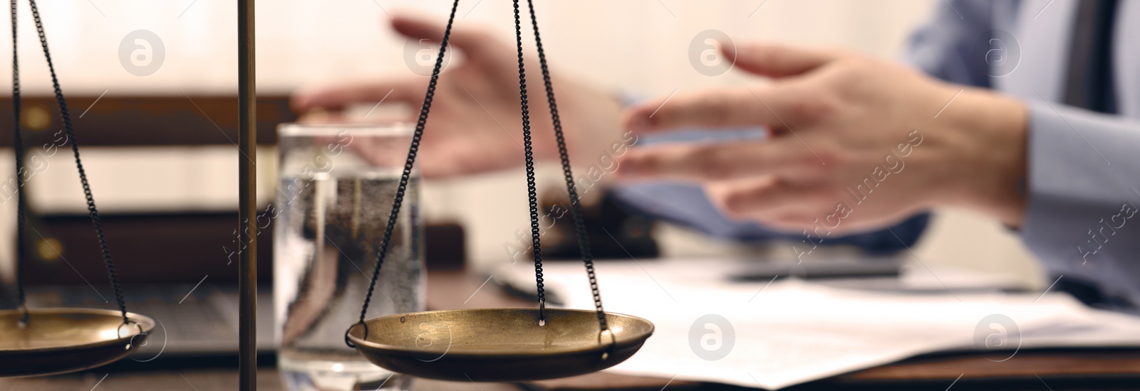 Image of Lawyer working at table in office, focus on scales of justice. Banner design