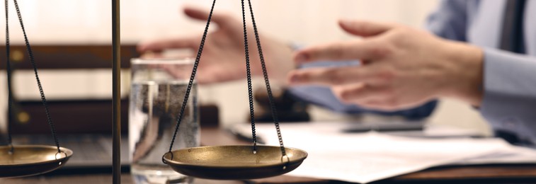 Image of Lawyer working at table in office, focus on scales of justice. Banner design