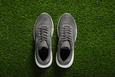 Pair of stylish sport shoes on green grass, flat lay