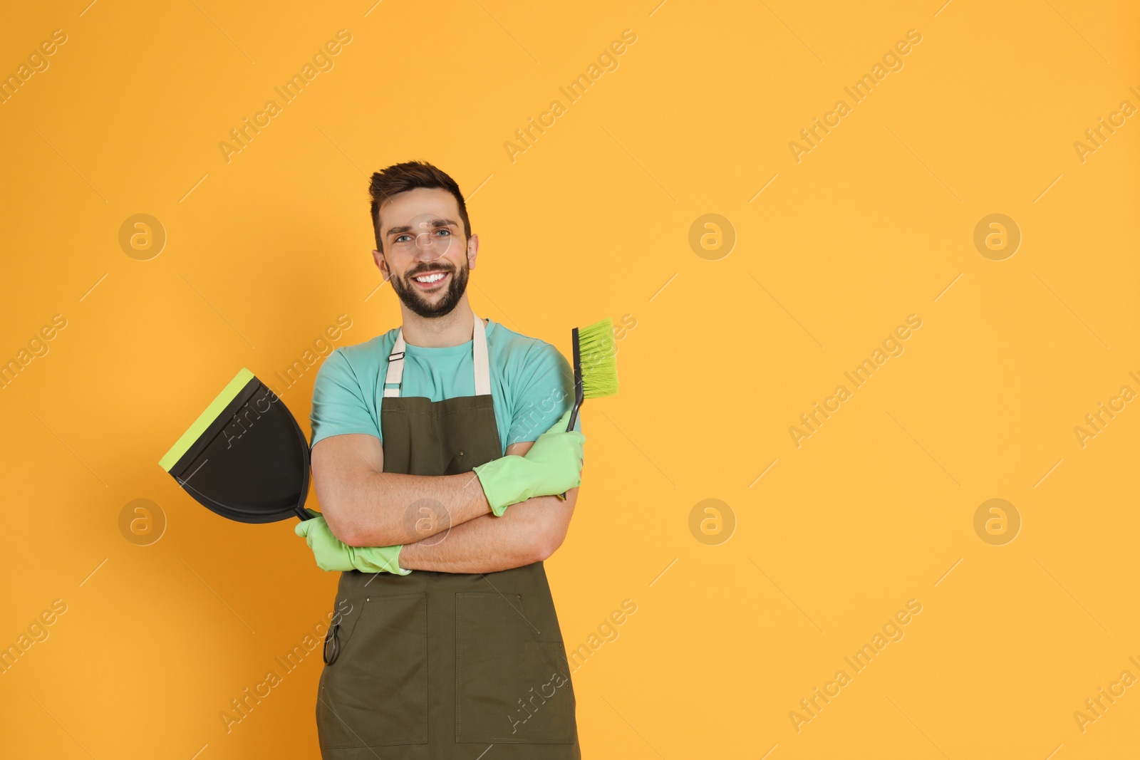 Photo of Man with brush and dustpan on orange background, space for text