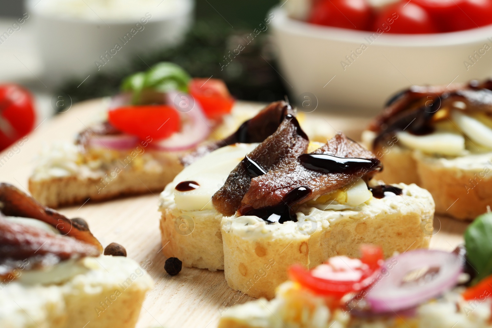 Photo of Delicious sandwiches with anchovies on wooden table, closeup