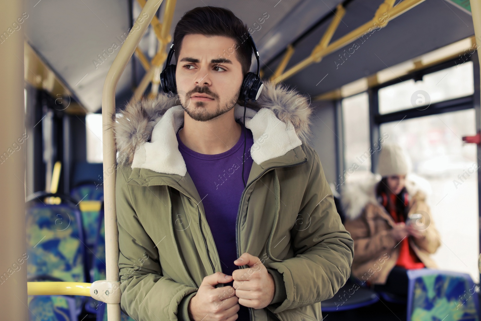 Photo of Young man listening to music with headphones in public transport