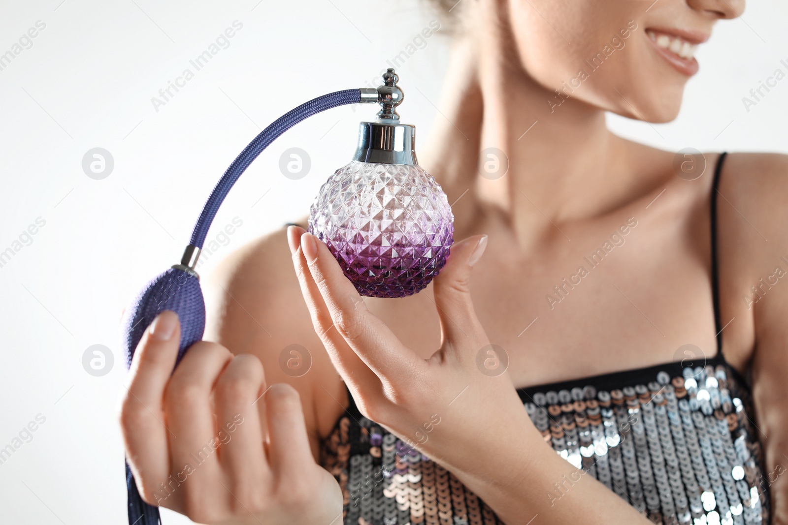 Photo of Young woman applying perfume against light background, closeup