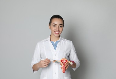 Photo of Doctor demonstrating model of female reproductive system on light grey background. Gynecological care