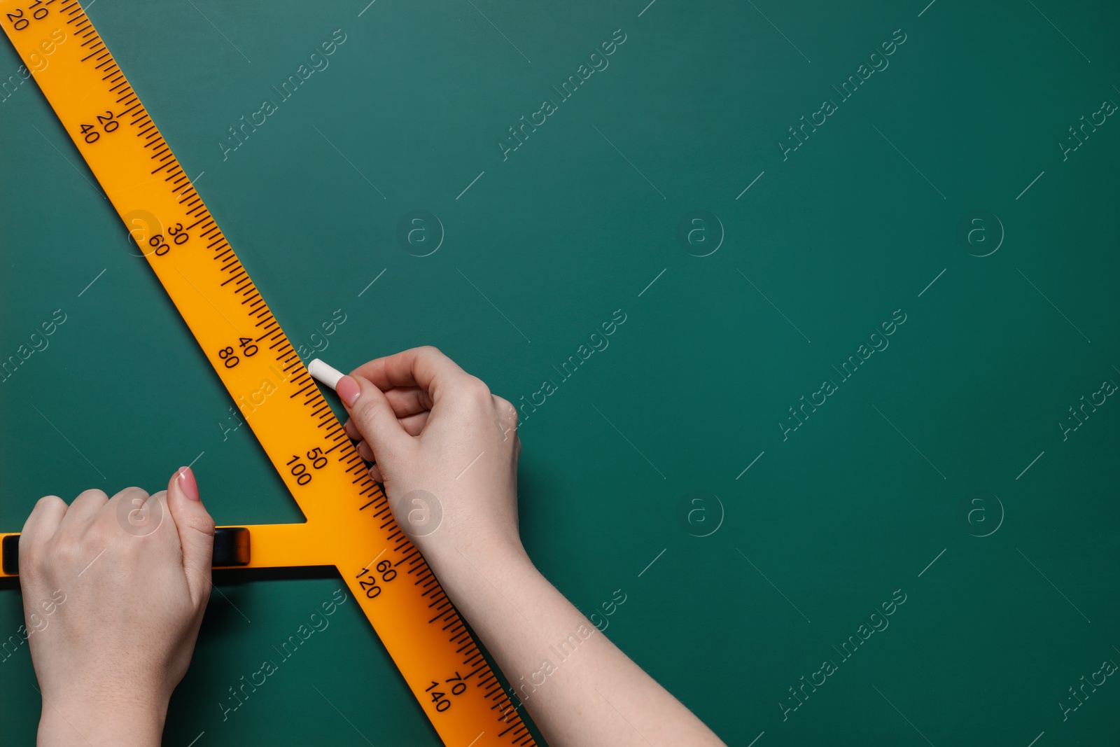 Photo of Woman drawing with chalk and triangle ruler on green board, closeup. Space for text