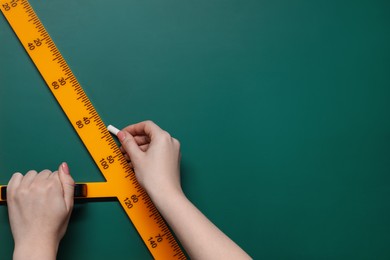 Woman drawing with chalk and triangle ruler on green board, closeup. Space for text