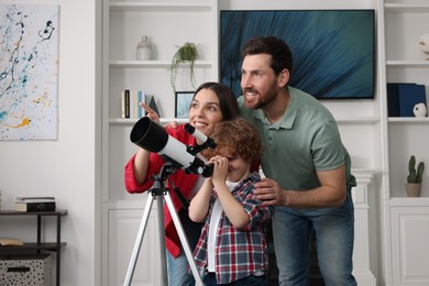 Happy family looking at stars through telescope in room