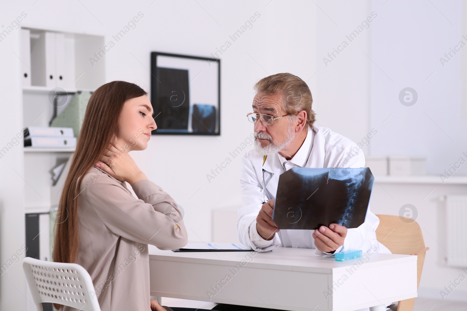 Photo of Orthopedist showing X-ray picture to patient in clinic