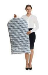 Photo of Young woman holding hanger with clothes in garment cover on white background. Dry-cleaning service