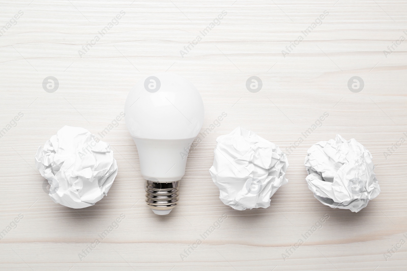 Photo of Creative flat lay composition with lightbulb and paper balls on white wooden table. Idea concept