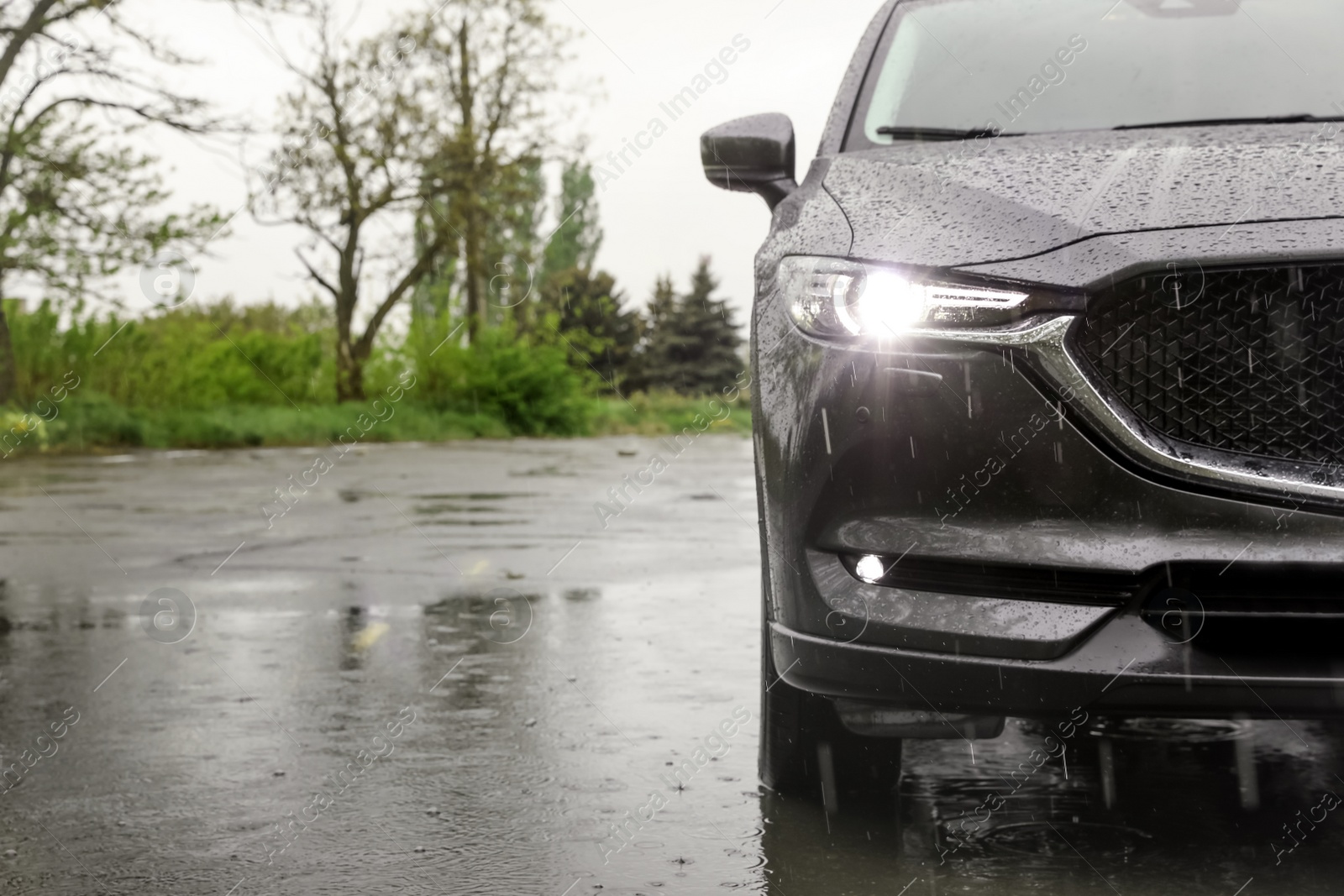 Photo of Modern car parked outdoors on rainy day