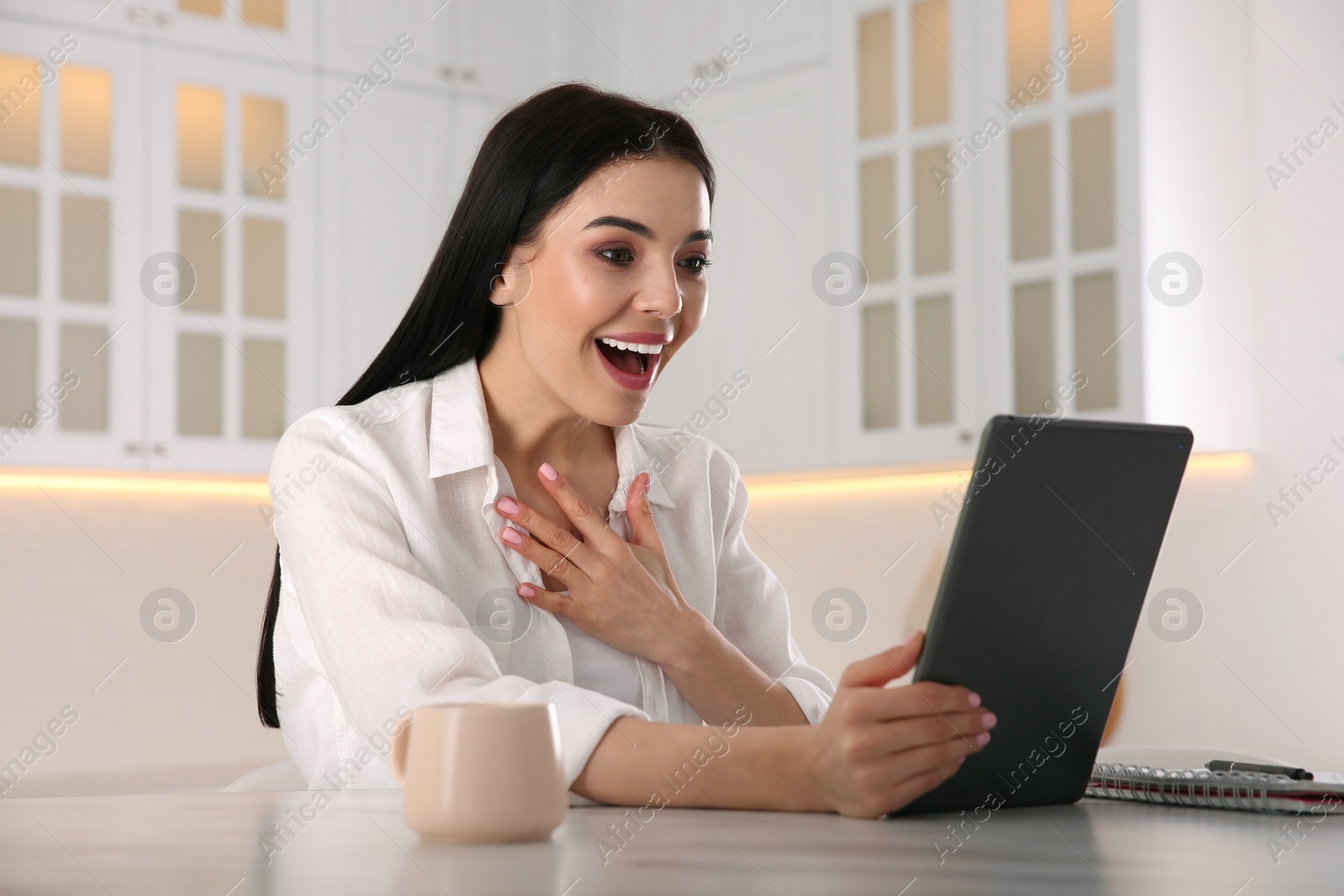 Photo of Emotional woman participating in online auction using tablet at home