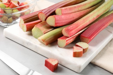 Whole and cut rhubarb stalks on white table, closeup