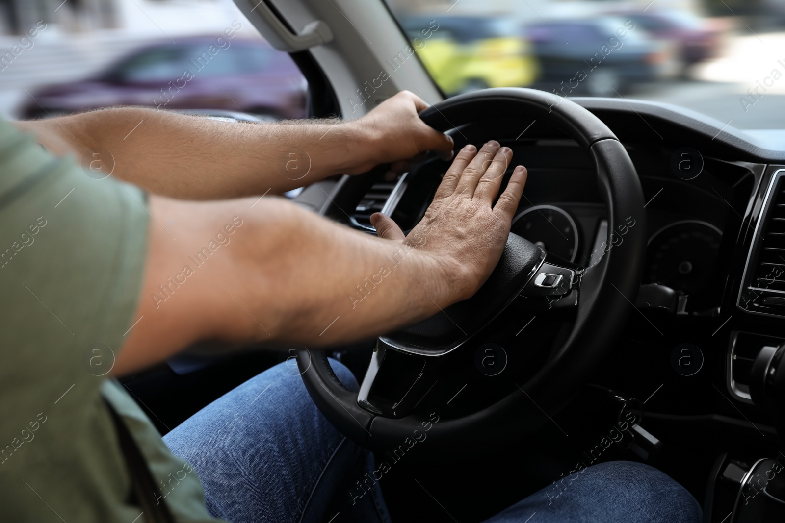 Photo of Man pressing horn in car, closeup. Aggressive driving behavior