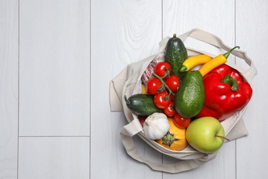 Photo of Bag full of fresh vegetables and fruits on light background, top view. Space for text