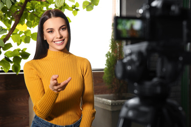 Young blogger recording video on camera indoors